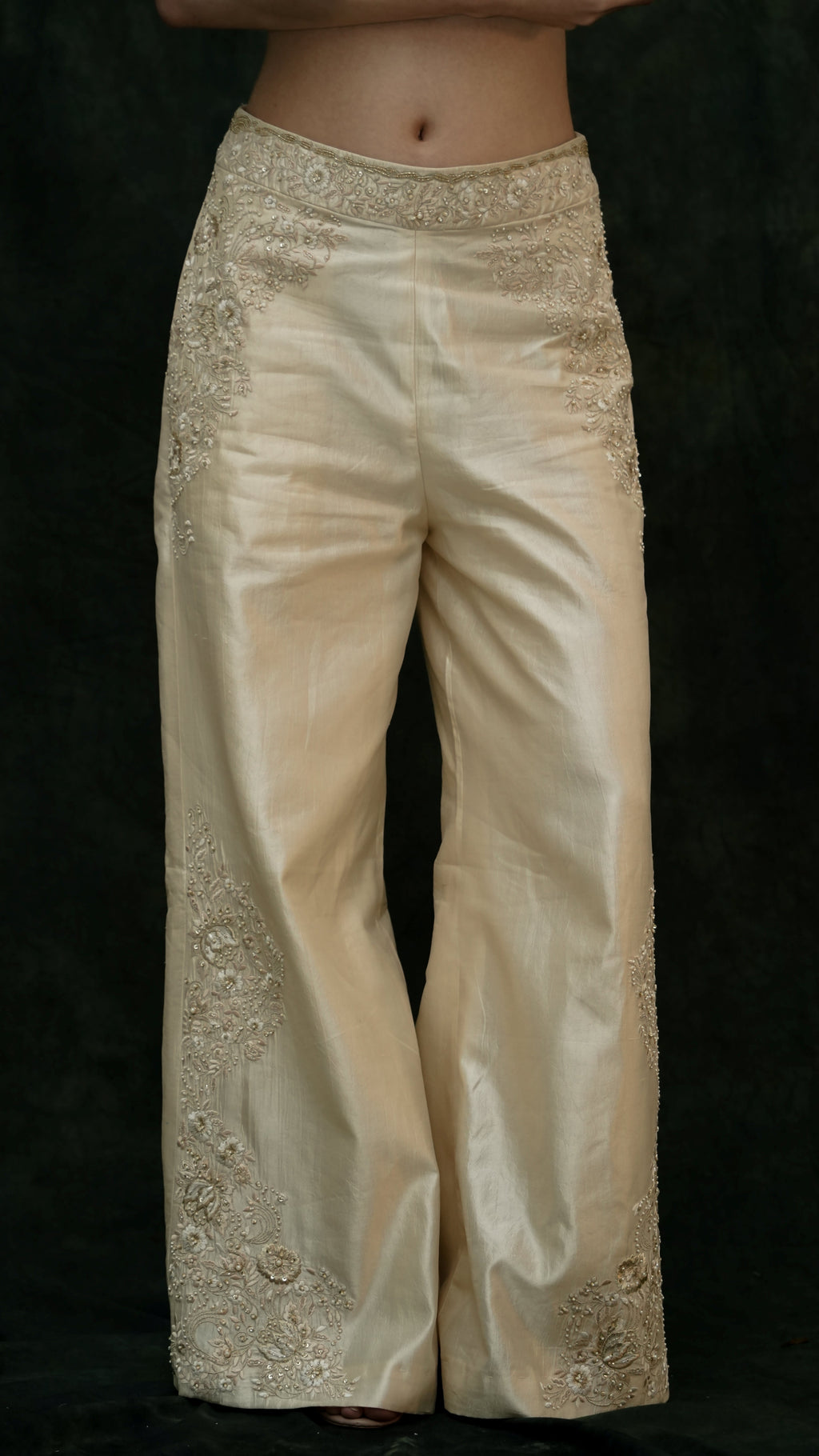Beige embroidered pants on a black background