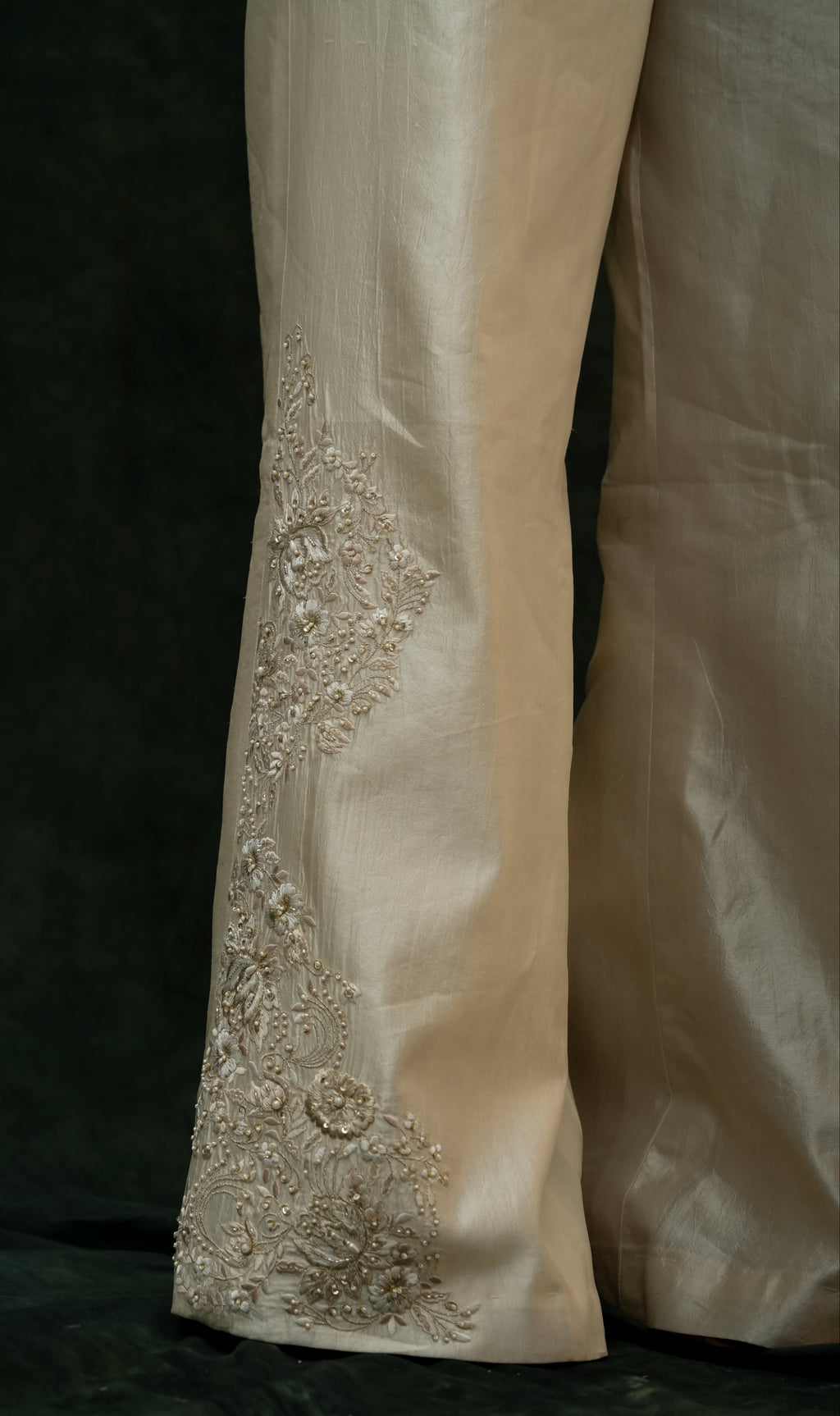 Close-up of a cream-colored fabric with intricate beadwork on a dark background