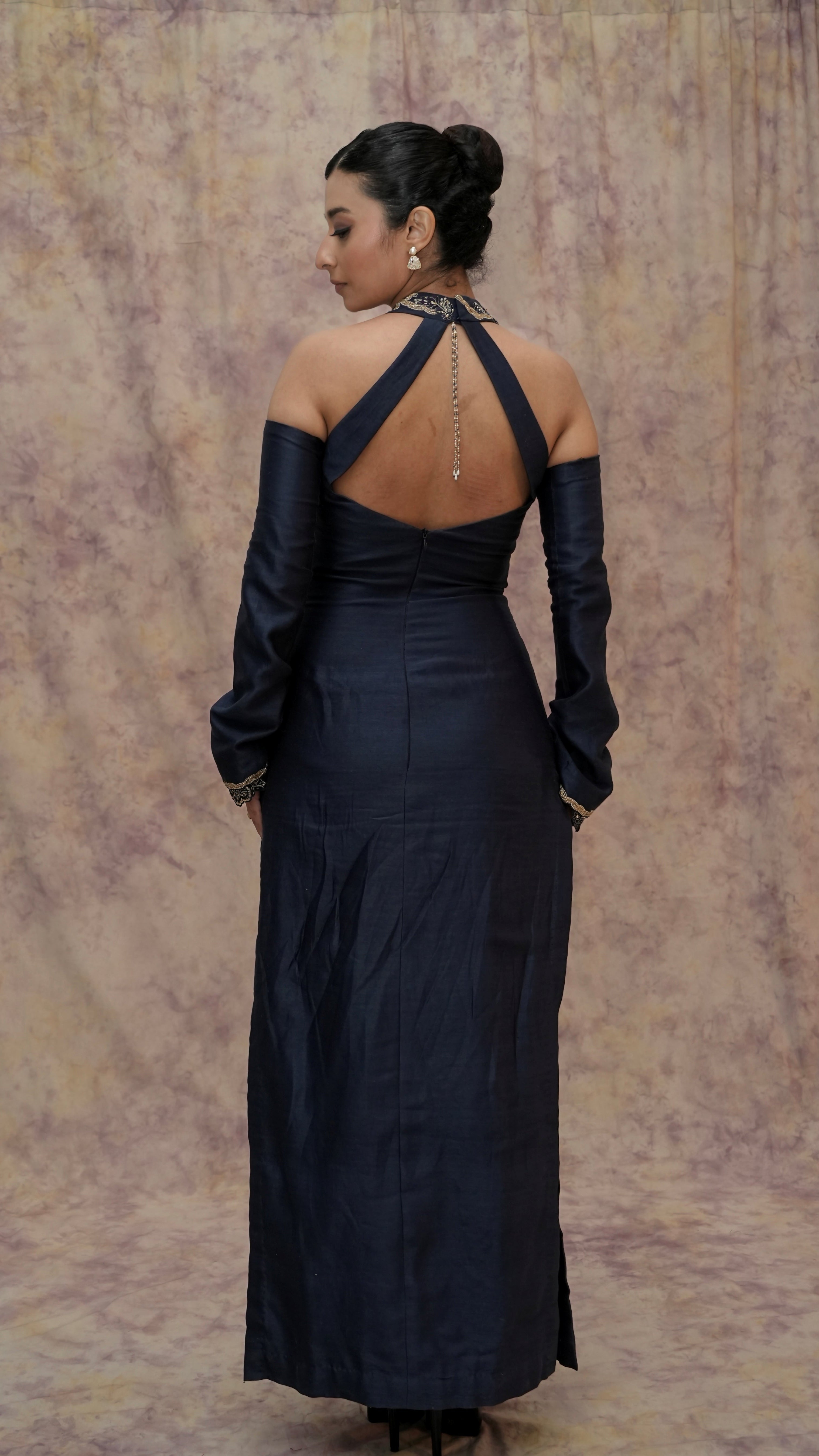 Woman wearing a black evening gown with sheer sleeves against a plain background