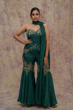 Woman in a green traditional outfit with intricate designs against a textured background