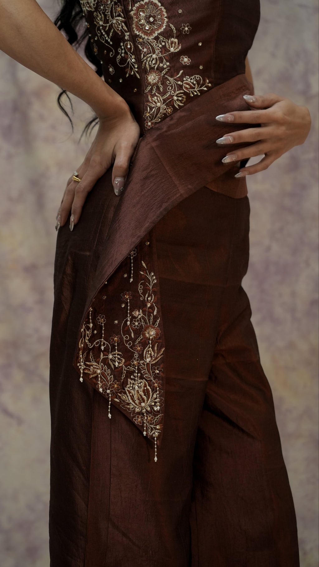 Brown dress with intricate gold embroidery on a textured background