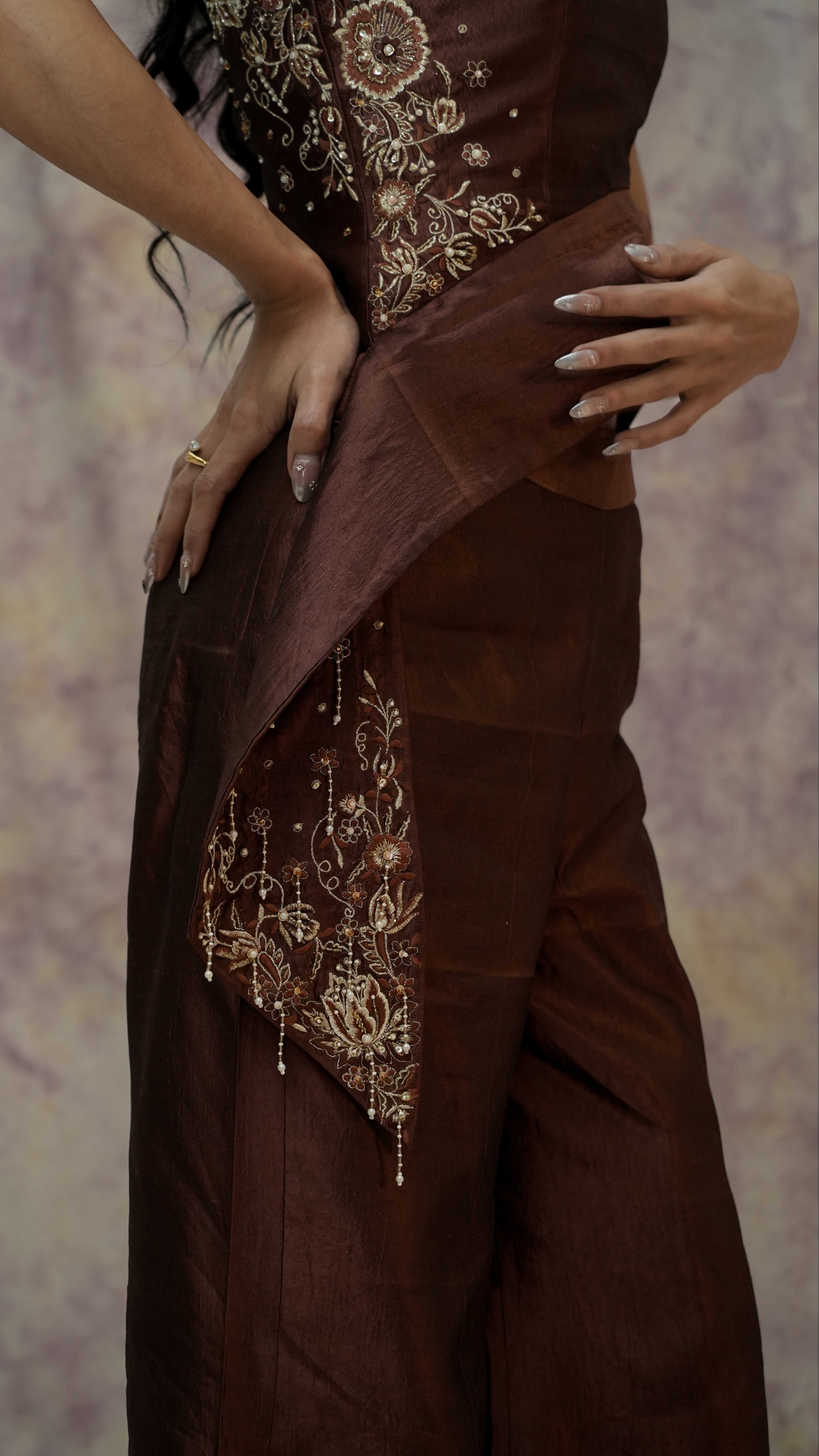 Brown dress with intricate gold embroidery on a textured background