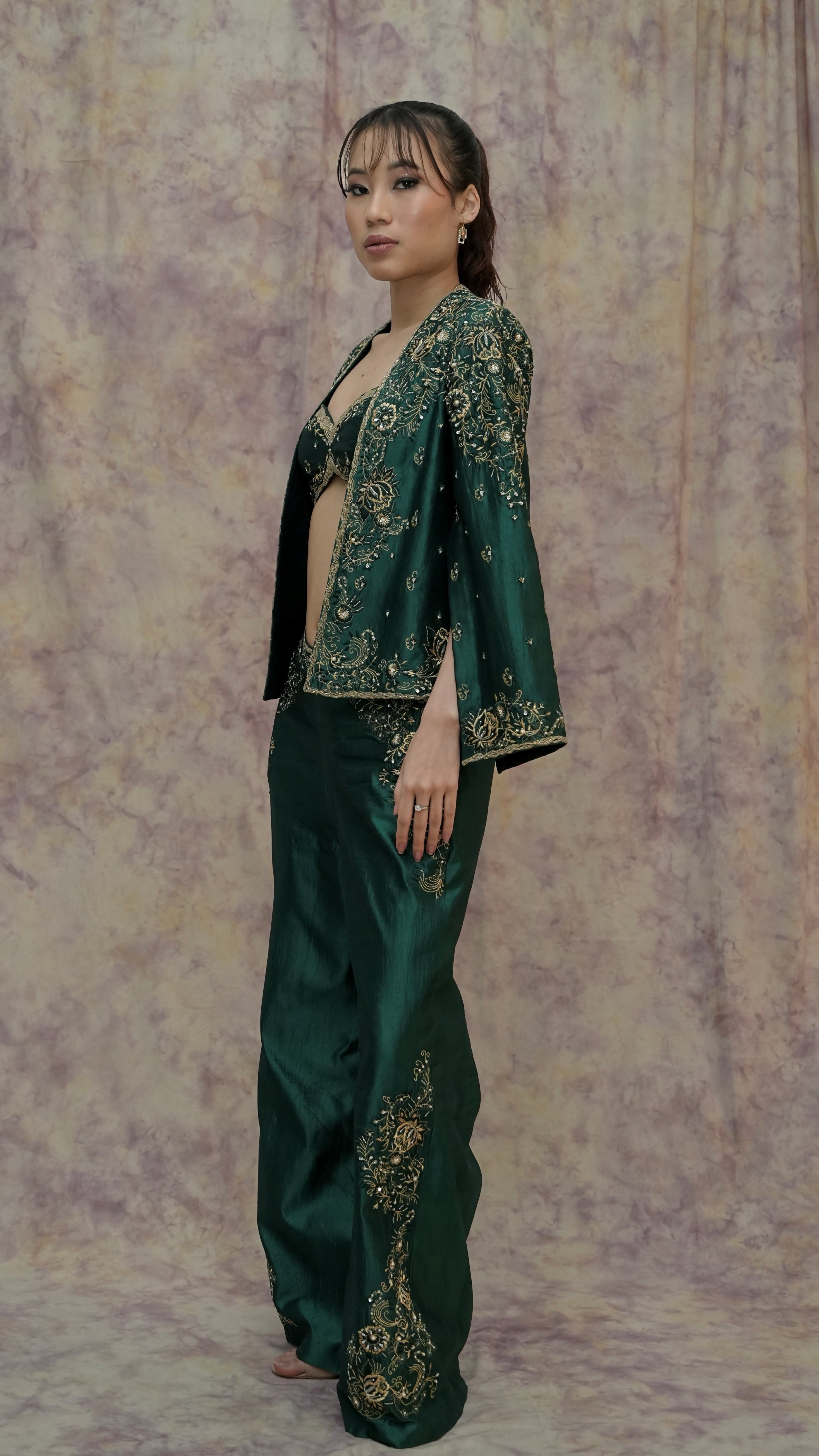 Woman wearing a green embroidered outfit against a textured purple background