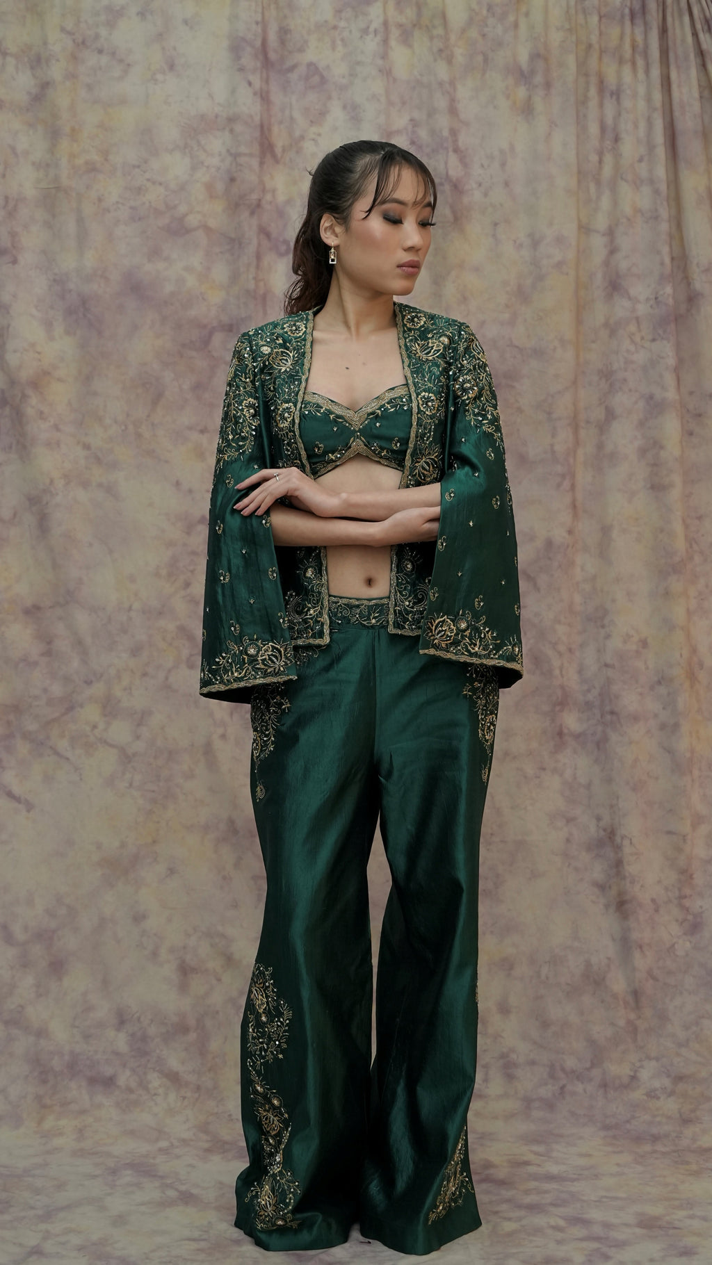 Woman wearing a green embroidered outfit against a textured purple background