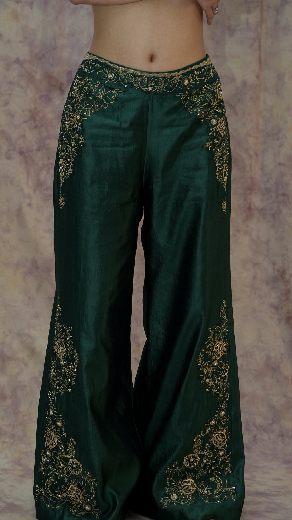 Green pants with gold embroidery on a textured background