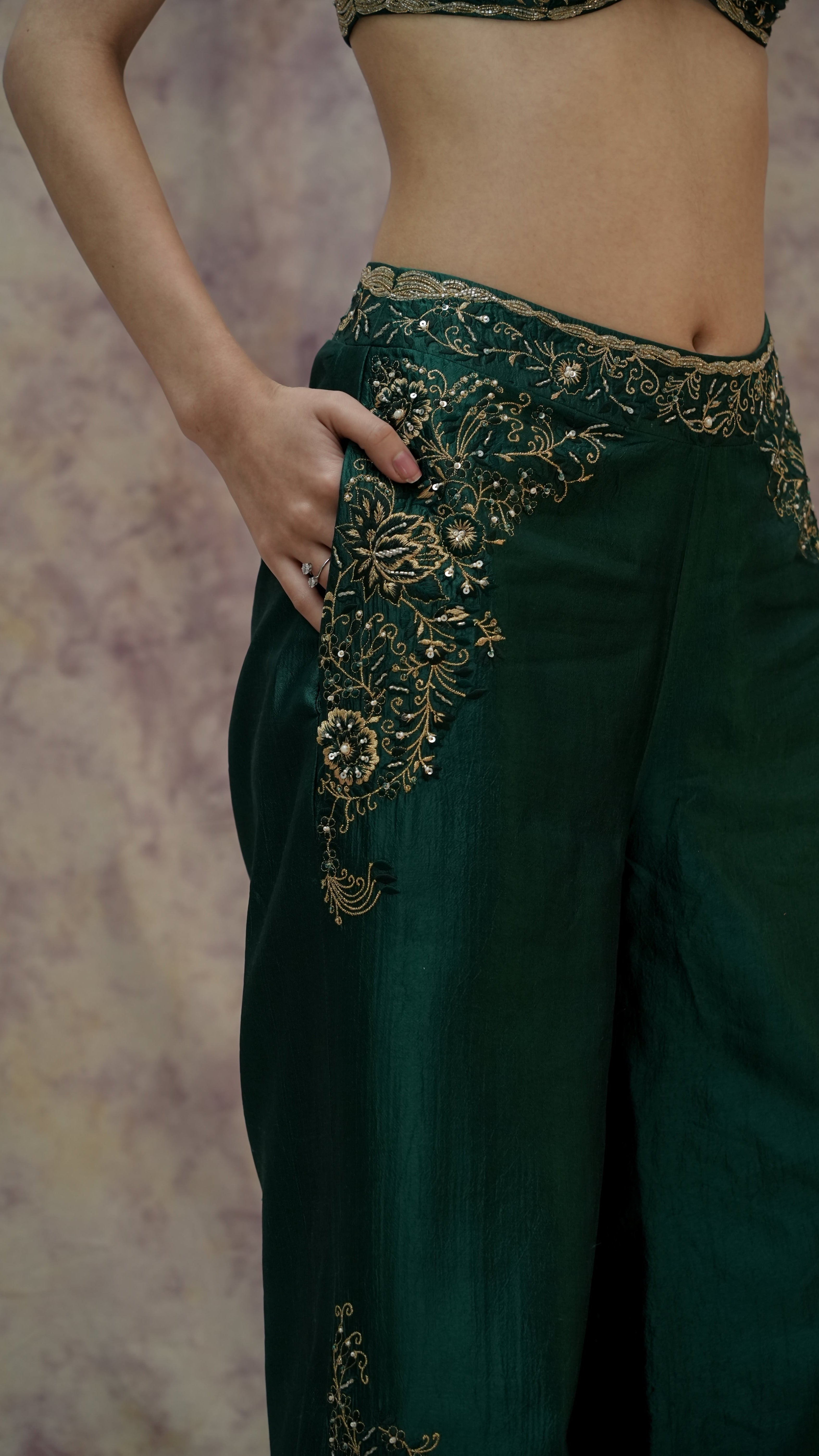 Green traditional outfit with intricate gold embroidery on a textured background