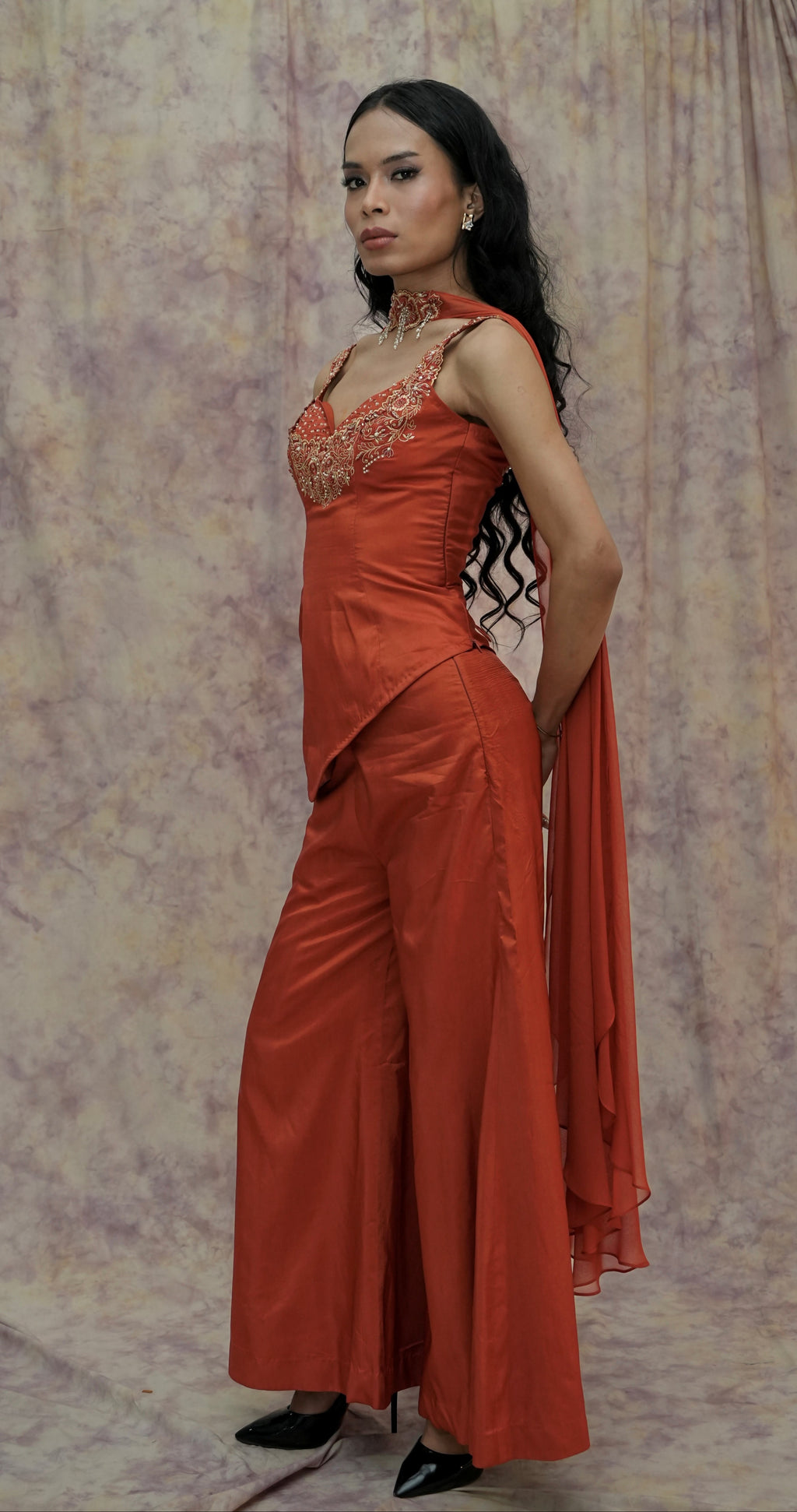 Woman wearing an orange evening gown against a patterned backdrop