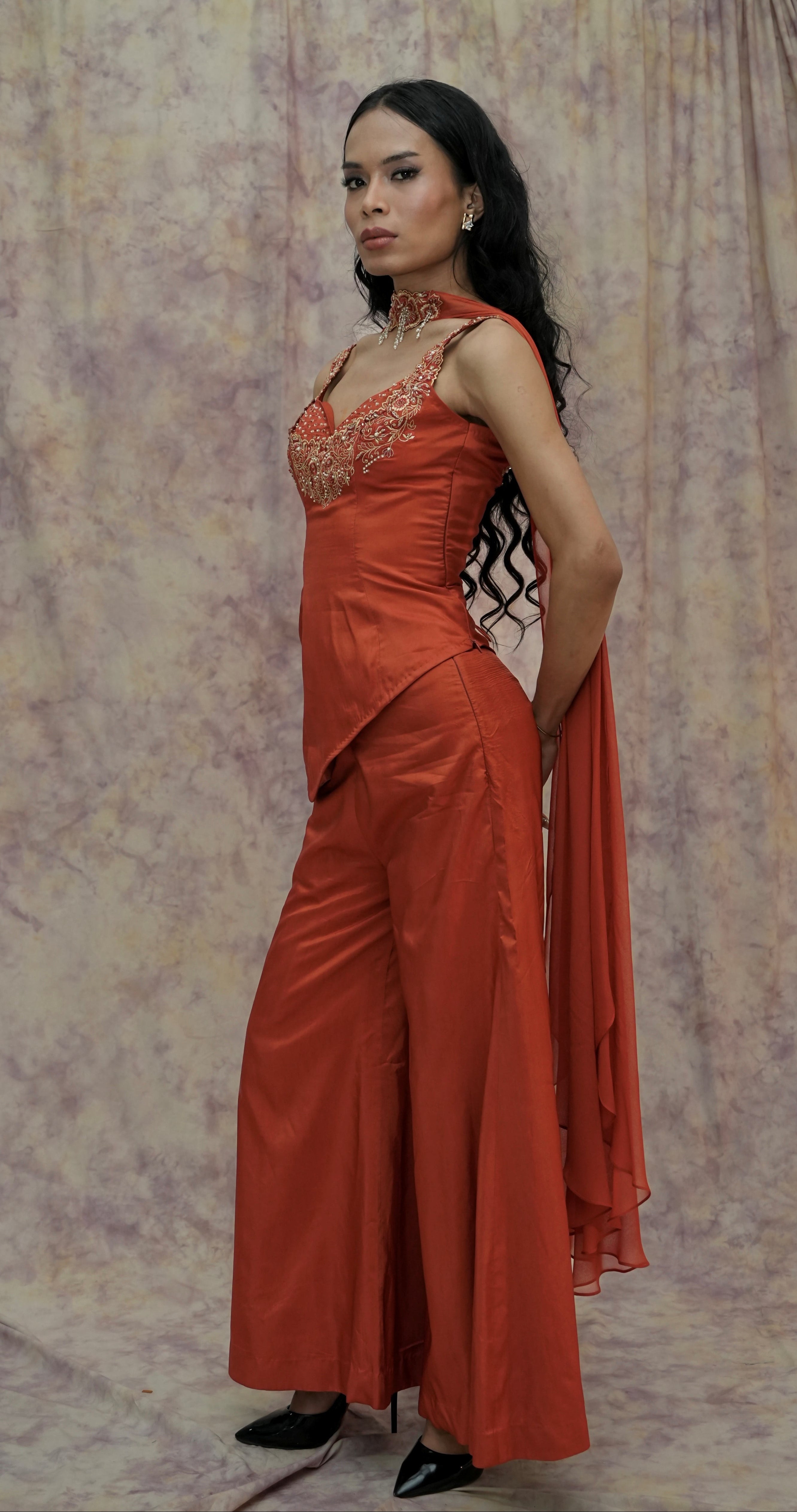 Woman wearing an orange evening gown against a patterned backdrop