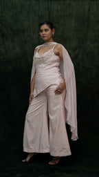 Woman wearing a light pink saree with a dark green background