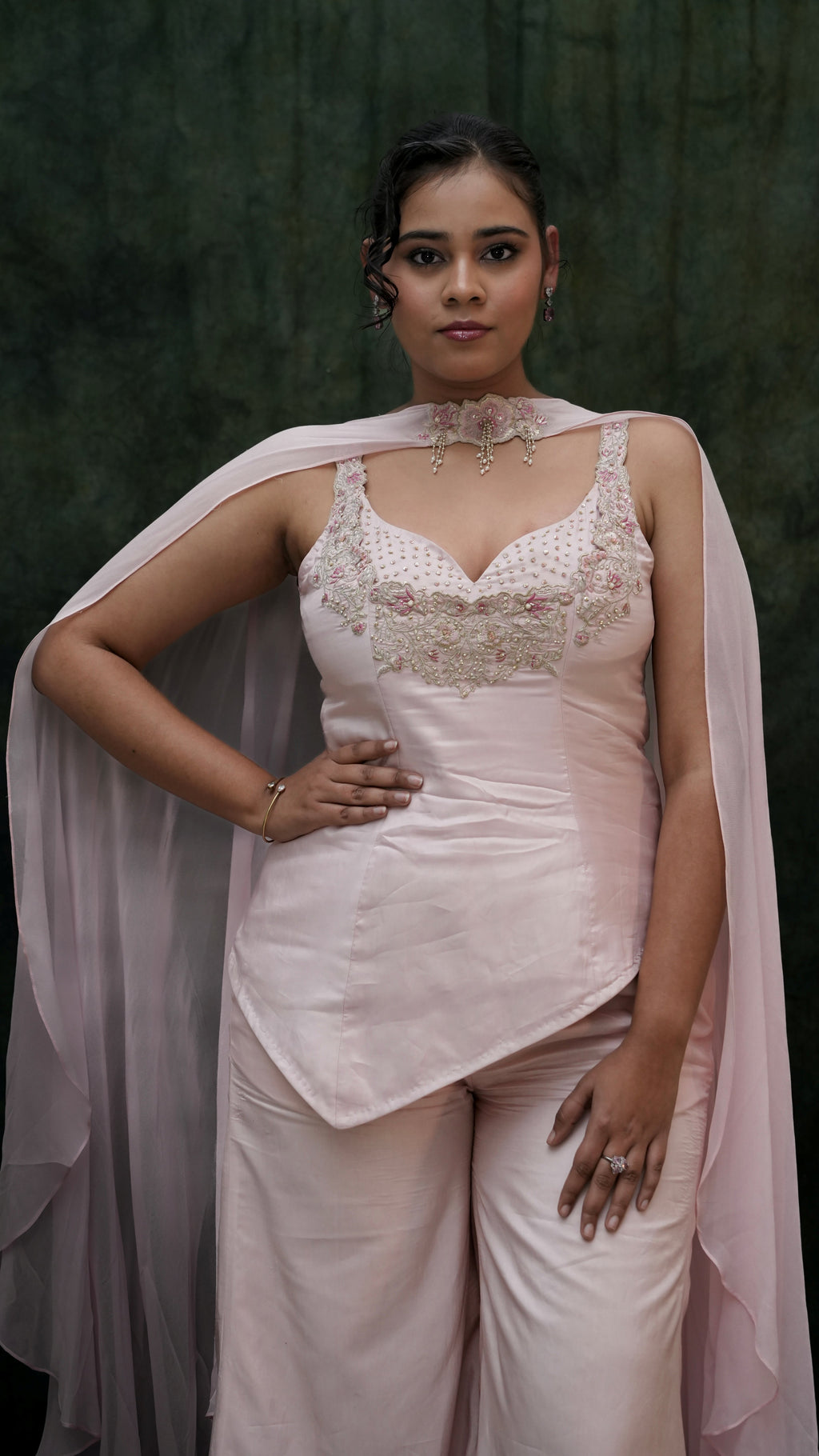 Woman wearing a white traditional outfit with a pink dupatta against a dark background