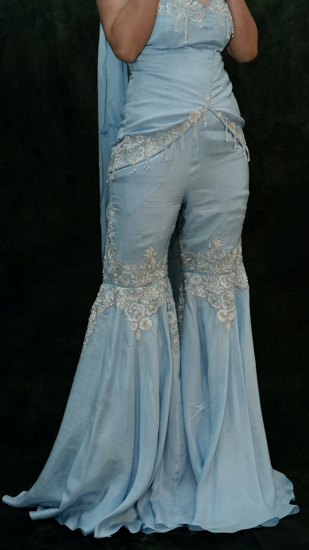 Light blue evening gown with intricate silver embroidery on a black background