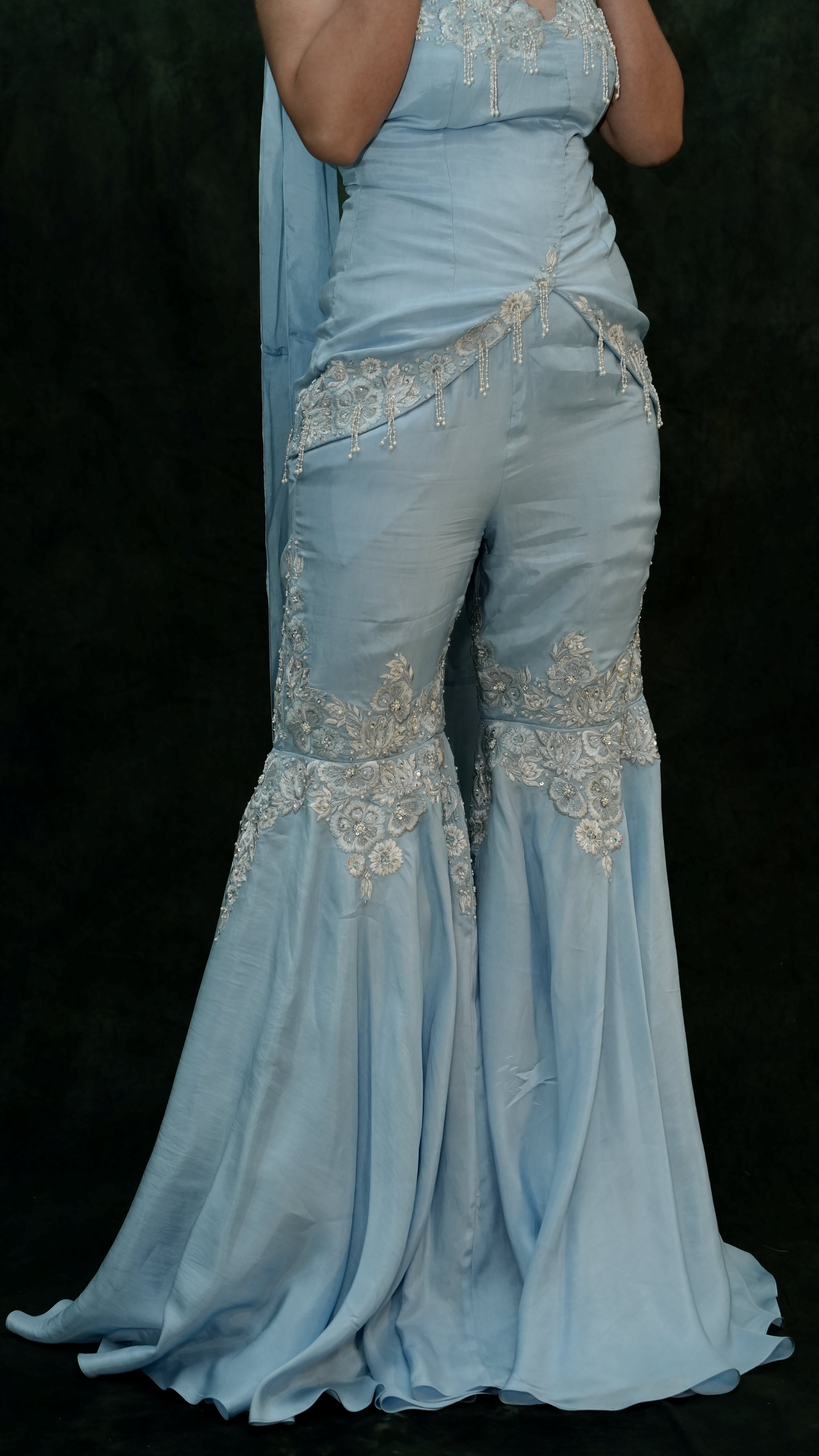 Light blue evening gown with intricate silver embroidery on a black background