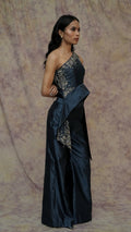 Woman wearing a dark blue evening gown with floral embroidery against a textured purple background