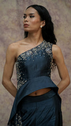 Woman wearing a dark blue saree with silver embroidery against a neutral background