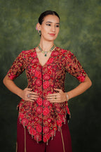 Woman wearing a red and brown patterned blouse with a green background