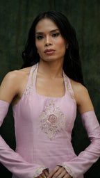 Woman wearing a pink traditional outfit with intricate designs on a dark background