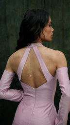 Woman wearing a pink dress with an open back against a dark green background