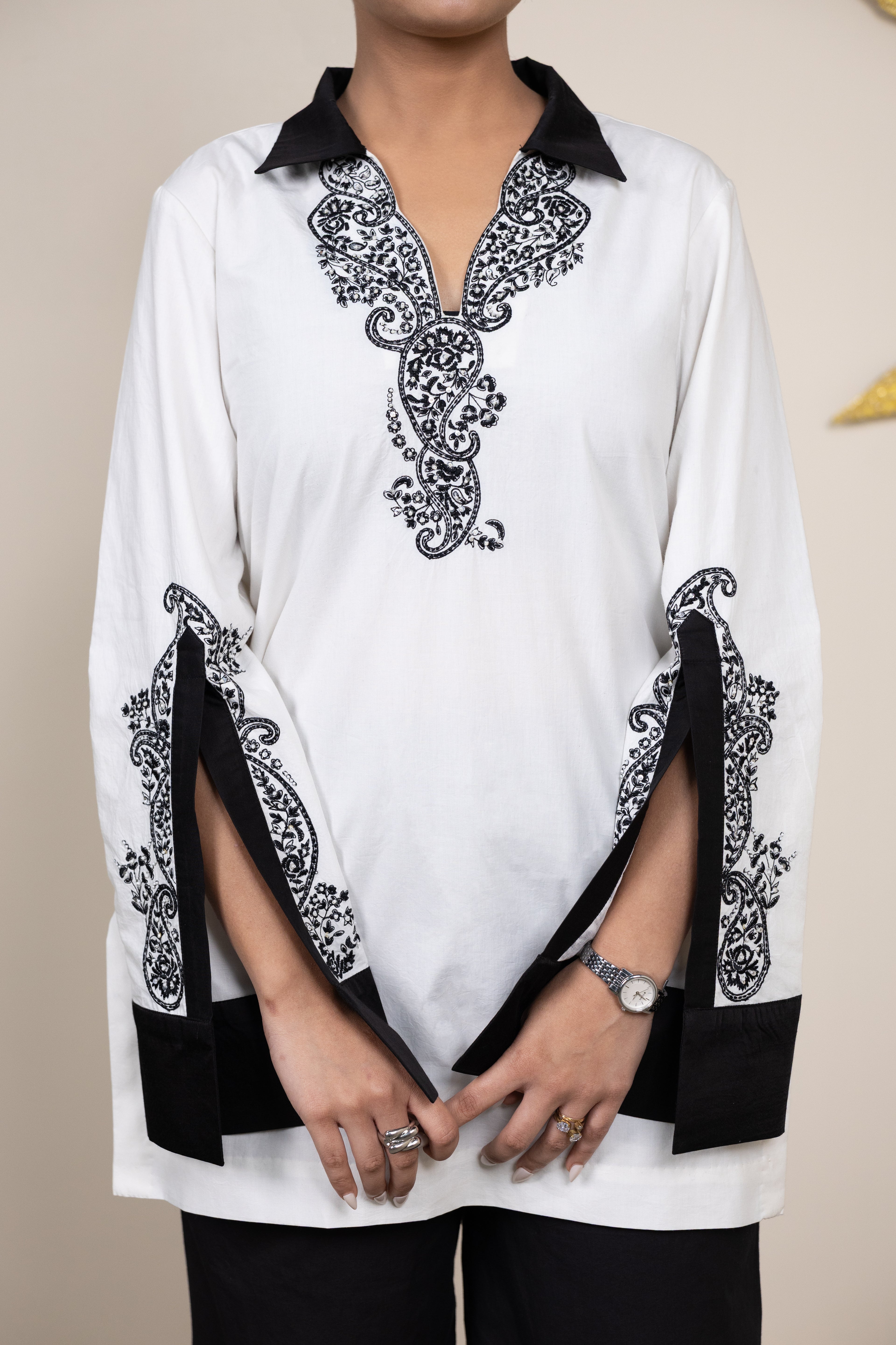 White top with black intricate patterns on a plain background