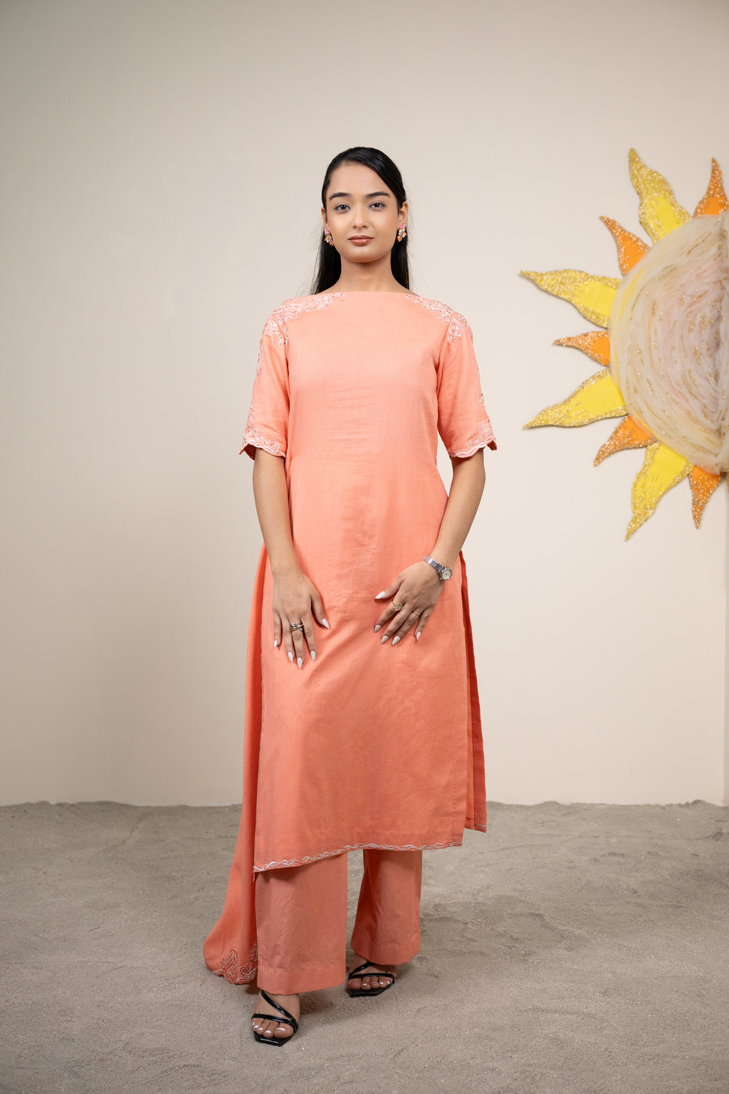 Woman wearing a peach kurta with a sun design in the background