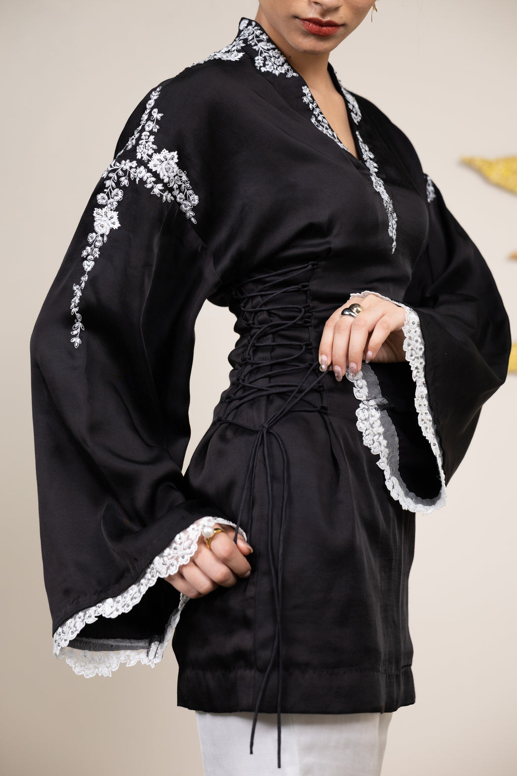 Black dress with white lace details worn by a person against a plain background