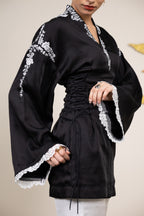 Black dress with white lace details worn by a person against a plain background