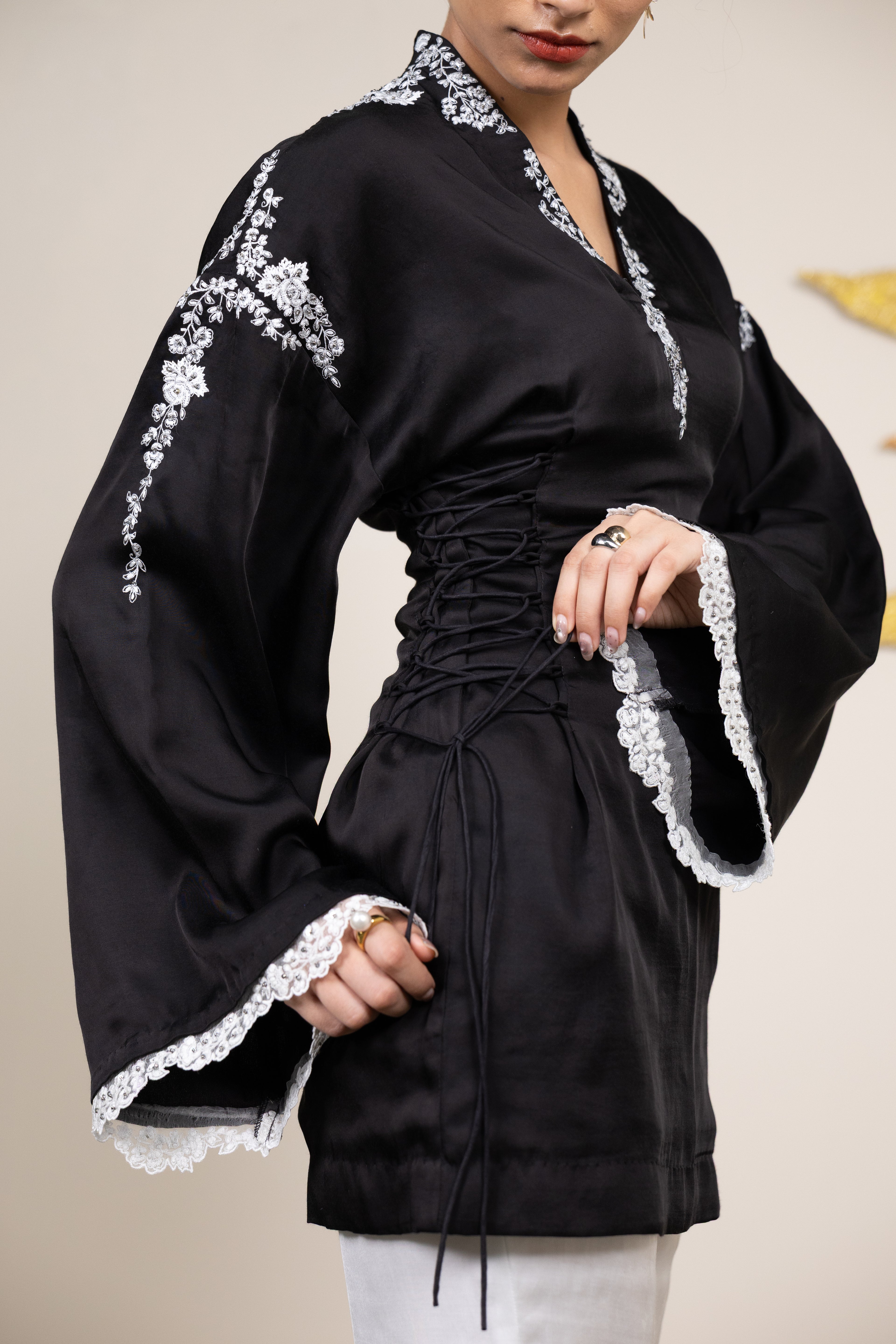 Black dress with white lace details worn by a person against a plain background