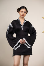 Woman wearing a black dress with white lace details on a beige background