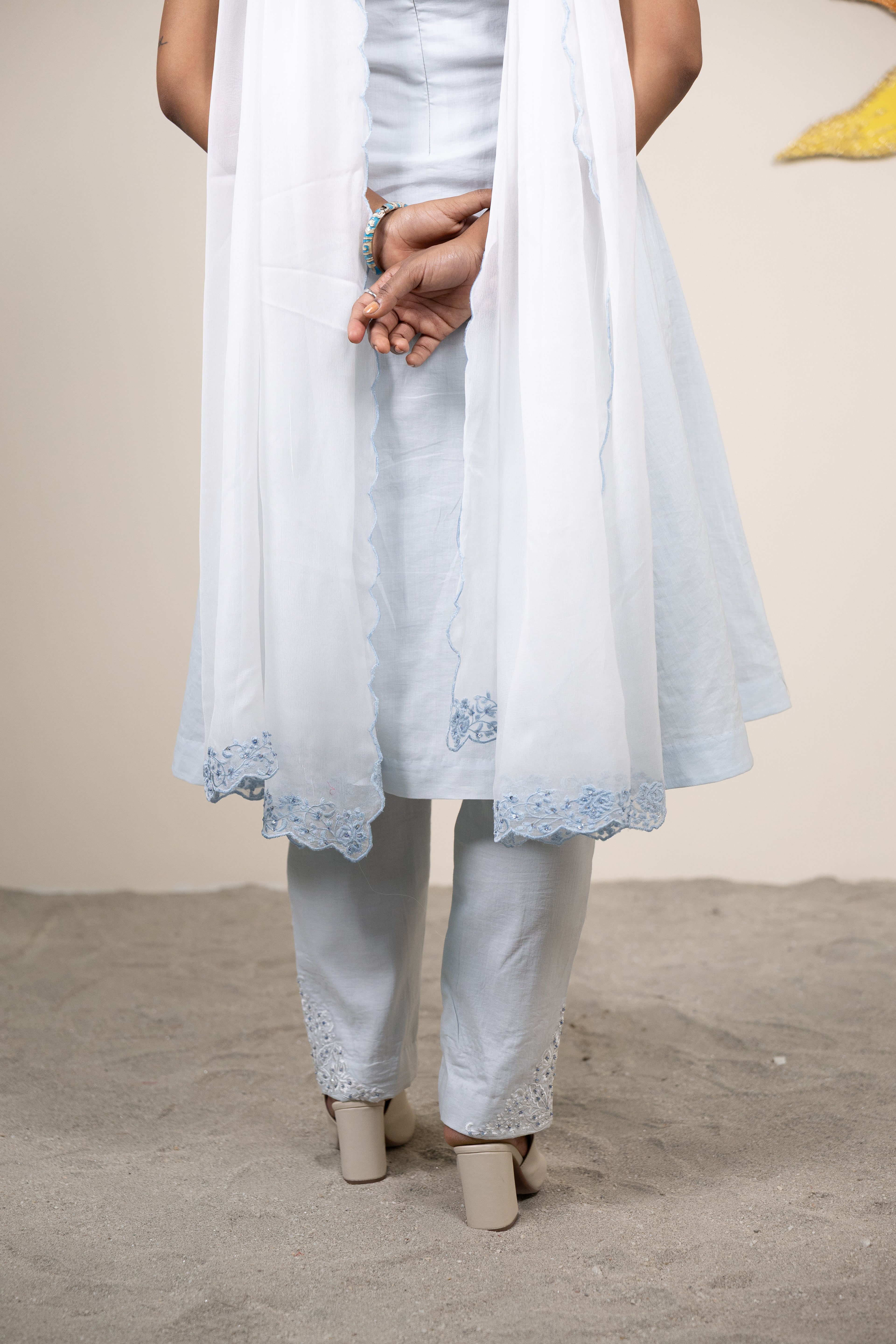 Person wearing a white outfit with lace details on a plain background