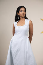 Woman wearing a white sleeveless dress against a beige background